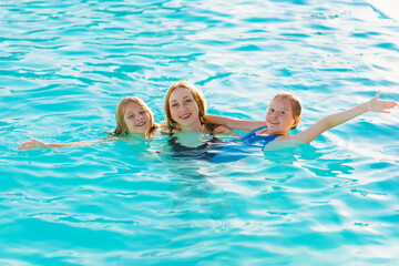Mom swims in the pool with her two daughters. 