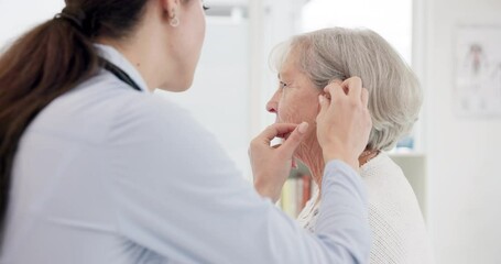 Female doctor, consultation and hearing aid on senior person at clinic for help with problem. Hearing, loss and deaf and installation for elderly woman at appointment with medical professional.