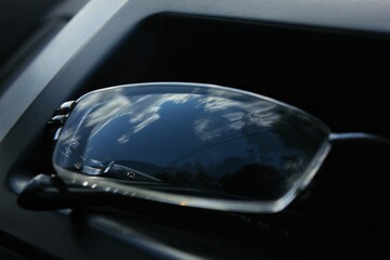 Close-up photo of ordinary transparent glasses in a car. The sky is reflected in the glass. 