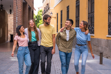 Group of embracing multiracial friends having fun in the city, friendship concept with guys and girls hanging out on the city street