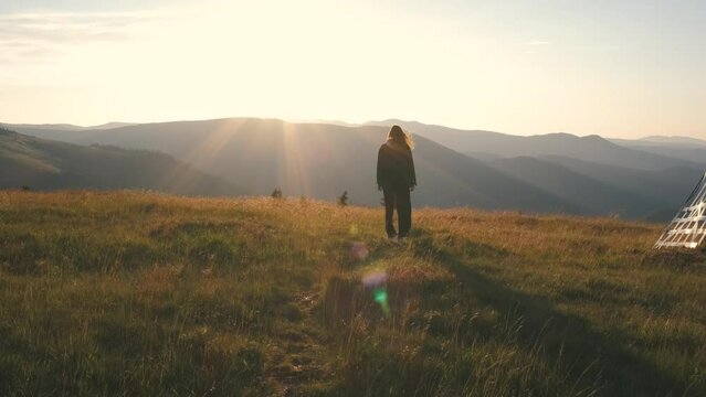 A beautiful Ukrainian young woman traveler walks along the most beautiful high mountain road in Romania Transalpina highway at sunset. Transalpina, Carpathian mountains in Romania at sunrise
