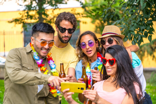 Multi ethnic group of friends partying in the city park taking a selfie, friendship and fun concept wearing sunglasses and drinking beer