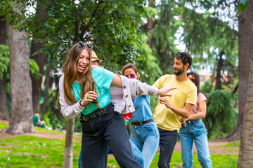 Group of multiethnic friends at birthday party in the city park dancing, summer fun doing the conga