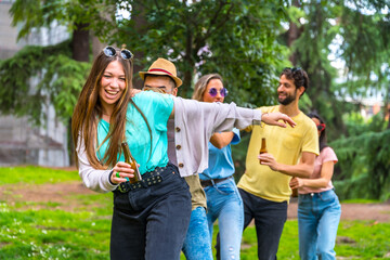 Group of multiethnic friends at birthday party in the city park dancing, summer fun doing the conga - obrazy, fototapety, plakaty