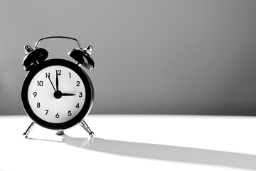 Modern black and white alarm clock in retro style isolated on white and grey background with shadow...