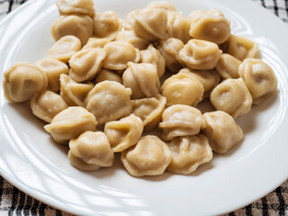 Big portion of Russian dumplings on a white plate. Tasty dinner. Classic west European dish.