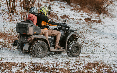 A young adventurous couple embraces the joy of love and thrill as they ride an ATV Quad through the snowy mountainous terrain