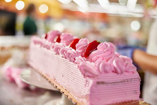 Female baker adding final touches to cake decoration in bakery of grocery store 