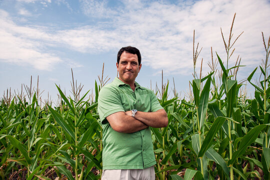 portrait of older man standing in corn field with arms crossed