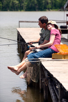 Couple Fishing From Dock On Small Lake, Woman Resting Head On Mans Shoulder 