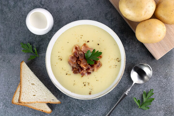 Potato soup puree with bacon, croutons and ingredients on a gray background. Top view. French vichyssoise soup.