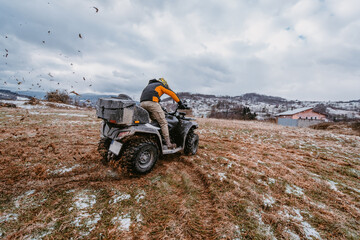 A man is fearlessly enjoying an adventurous ride on an ATV Quad through hazardous snowy terrain, embracing the thrill and excitement of the challenging mountainous landscape