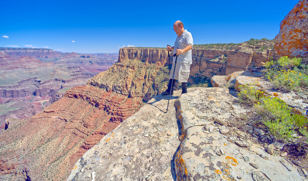A hiker on the edge of a cliff between Moran Point and Zuni Point at Grand Canyon Arizona.