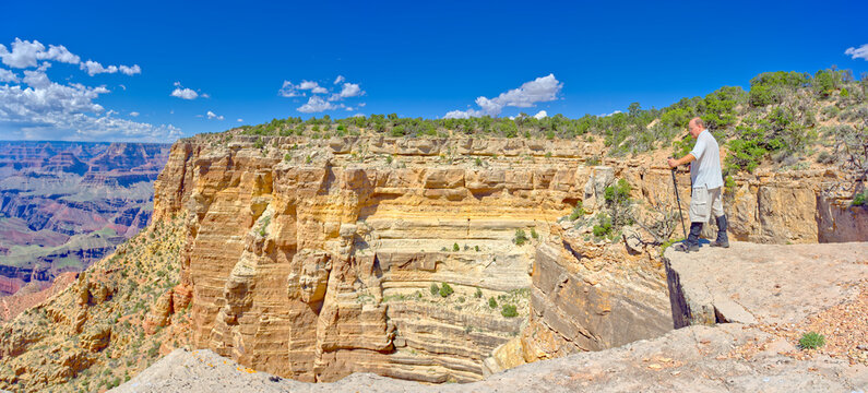 A hiker standing on a cliff near the Zuni Abyss with Zuni Point on the left at Grand Canyon Arizona.