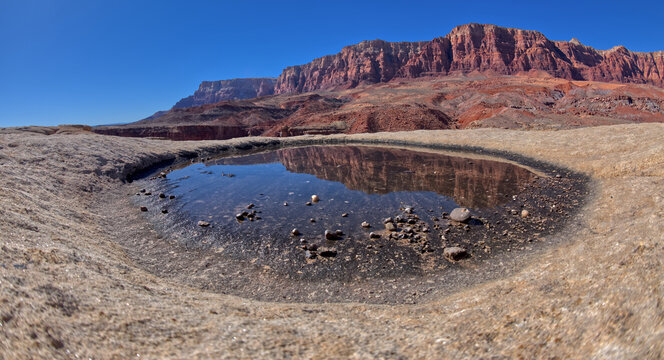 A pool of reflecting water on the summit of Johnson Point below Vermilion Cliffs at Glen Canyon Recreation Area Arizona.