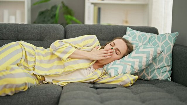 Young blonde woman lying on sofa using smartphone sleeping at home