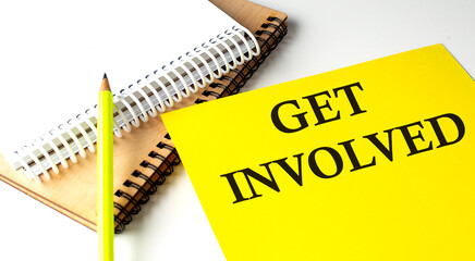 GET INVOLVED text written on a yellow paper with notebook