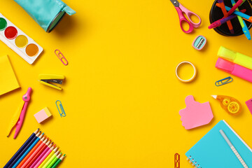 Frame of school supplies on yellow background. Back to school concept. Flat lay, top view.