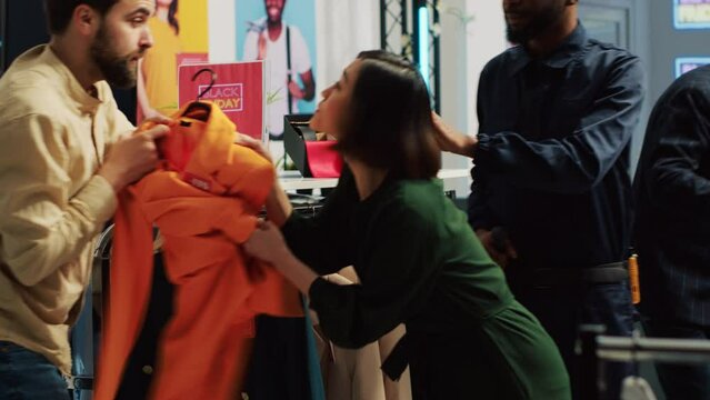 People into shopping madness during black friday sales, arguing over clothes with big discount. Angry customers pulling merchandise and being obsessed over promotional clearance items.