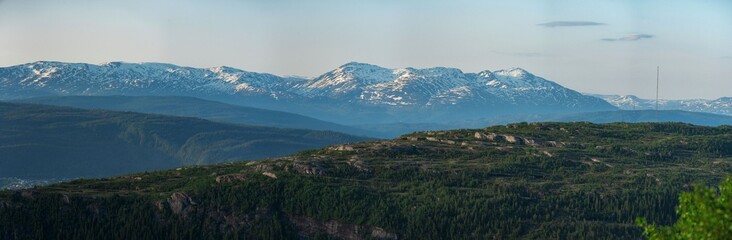 Panorama over nordic mountain peaks in Norway from a hike up Hauknestinden, Hauknes, Mo i Rana, Helgeland, Norway. Peaks in a fjord landscape, snow covered. Clear Norwegian summer skies. Wild Norway