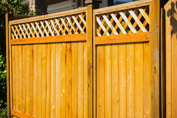 Nice new wooden fence around house. Wooden fence with toppers. Red wood fence with lattice panels.