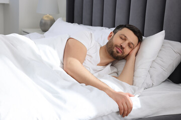 Handsome man sleeping in soft bed at home