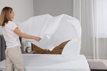 Woman changing bed linens at home. Space for text