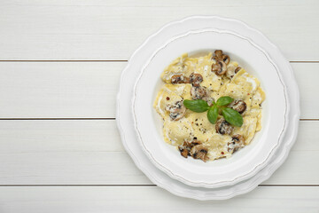 Delicious ravioli with mushrooms and cheese on white wooden table, top view. Space for text