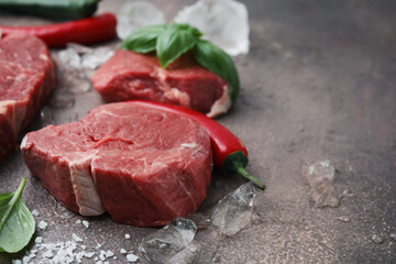 Fresh raw cut beef, ice cubes and spices on brown table, closeup. Space for text