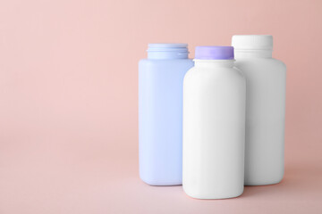 Baby powder in bottles on light coral background, space for text