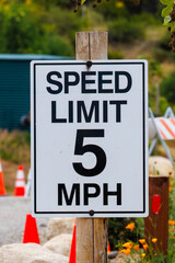 White sign with black letters indicating 5 mile per hour speed limit
