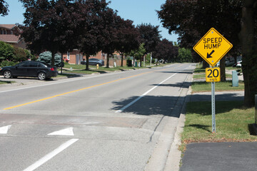 medium on speed hump arrow 20 km/h sign in black writing on yellow background silver post with...