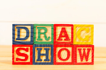 Spectacular colorful letters on wooden cubes on a wooden board with the word drag show.