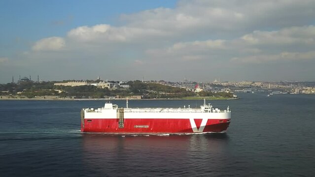 Ro-Ro ship sails past the Old Istanbul City. Aerial. Pure car and truck carrier underway in Bosphorus Sea. Vehicles carrier in front of the Sarayburnu Coast
