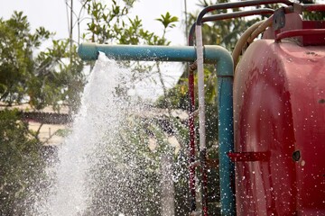 a photography of a red fire hydrant spraying water on a tree, there is a red fire hydrant spraying...