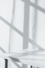 Empty tabletop with window shadow on concrete wall texture background, suitable for product presentation backdrop.
