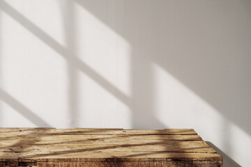 Empty tabletop with window shadow on concrete wall texture background, suitable for product presentation backdrop.