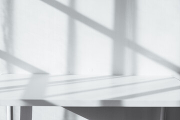 Empty tabletop with window shadow on concrete wall texture background, suitable for product presentation backdrop.