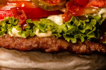 Bacon burger with onions tomatoes cucumber lettuce. Fast junk food abstract photo
