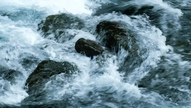 Slow motion of abundant stream of water flowing in a mountain river.
