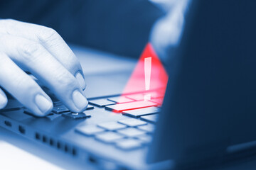 Alert warning. Caution sign on a laptop keyboard. Close up of an unrecognizable person keyboarding. Cyber attack on the network. Computer security concept.