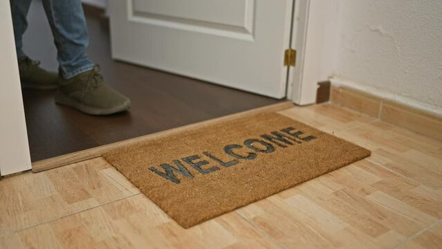 Young latin man putting package on doormat at home