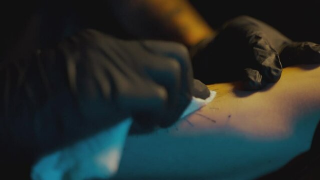 Hand-poke Tattoo Artist Wiping Out The Excess Ink From The Skin Of Customer Using Tissue. - close up