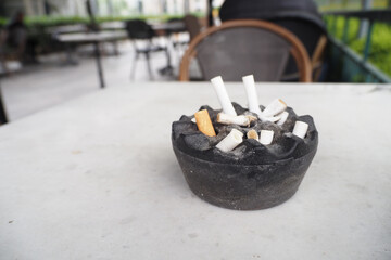 Close up burning cigarette in ashtray on table 
