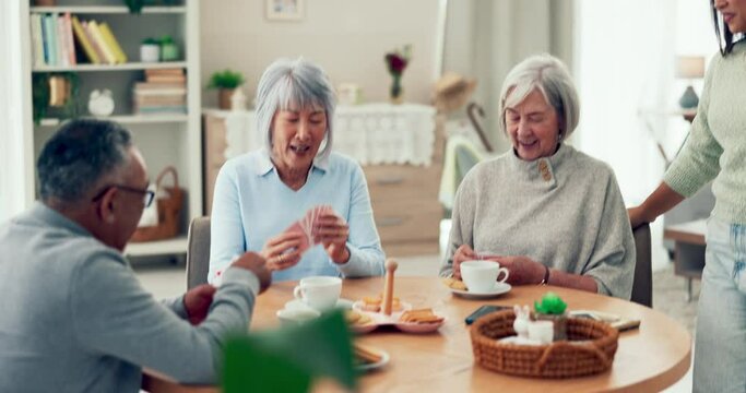 Senior people, friends and playing cards at a table while laughing and talking in nursing home. Elderly women, man and caretaker with tea and a game for bonding and to relax together in retirement
