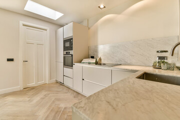 a kitchen with white cabinets and marble counter tops in the center of the room, there is a skylight