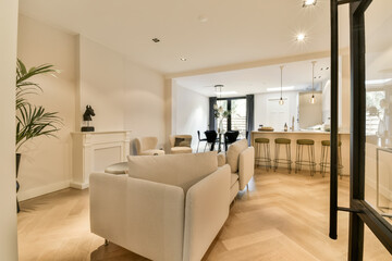 a living room with wood flooring and white furniture in the photo is taken from the front door to the kitchen area