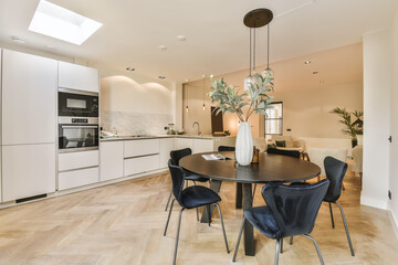 a kitchen and dining area in a house with white walls, wood flooring and an open skylight above the...