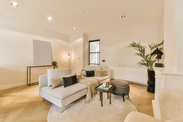 a living room with white walls and wood flooring in the center of the room is a couch, coffee table, side tables