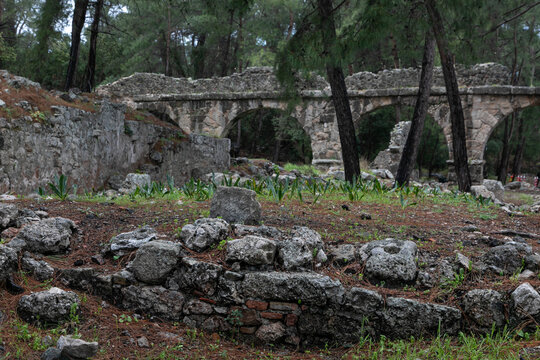 Huge stone arch in the middle of ancient ruins and ruined walls. The remains of ancient Lycia civilization, Phaselis antique city in Turkey. Mediterranean landscape